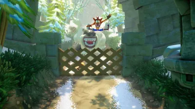 Crash Bandicoot jumping over a fence in a jungle environment with a large creature in the background.