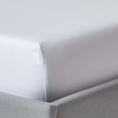 A close-up view of a white fitted sheet on a bed.