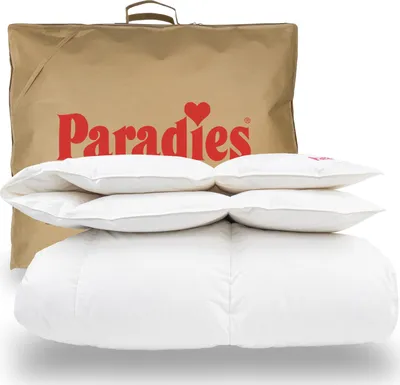 A folded duvet and pillows are stacked in front of a branded fabric bag.