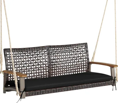 A brown wicker-like swing bench with a black cushion and wooden armrests, suspended by ropes against a white background.