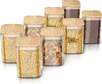 A set of glass storage jars with bamboo lids filled with pasta and coffee beans, arranged on a white background.