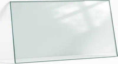 A clear glass tabletop leaning against a textured white wall, with soft shadows cast on the wall.
