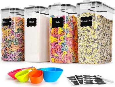 A set of four clear plastic food storage containers filled with different dry goods, along with measuring cups and labels.