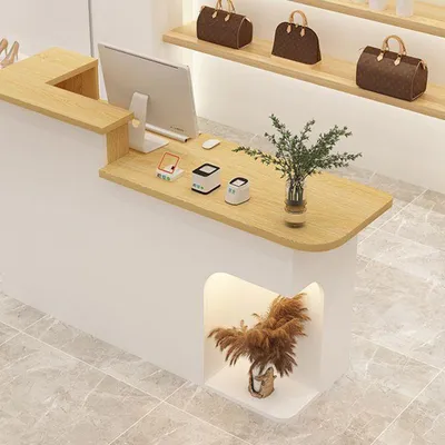 A reception desk in a retail store with a computer, payment terminals, and decorative plants.