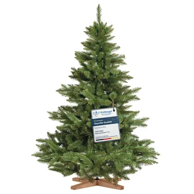 A green artificial Christmas tree with a wooden stand, featuring a tag with product information.