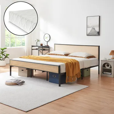 A bedroom scene featuring a bed with a rattan headboard and a mattress, along with bedside tables and decor.