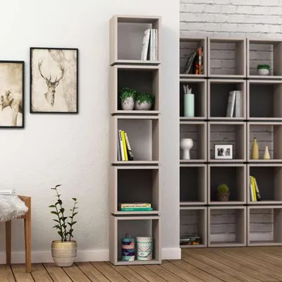 A modern living room with a tall, narrow bookshelf unit filled with books and decorative items, next to a wall with framed artwork.