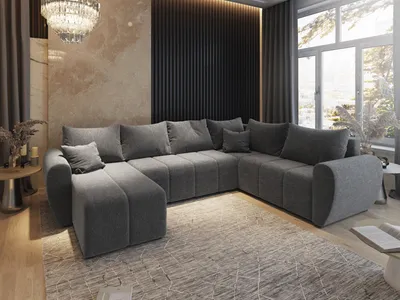 A modern living room featuring a large grey sectional sofa with an ottoman, set on a patterned rug.