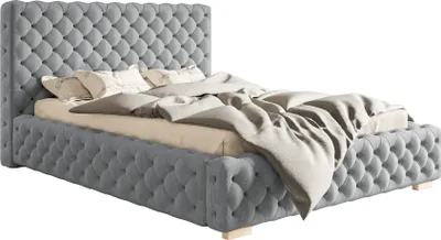A tufted gray upholstered bed with beige bedding.
