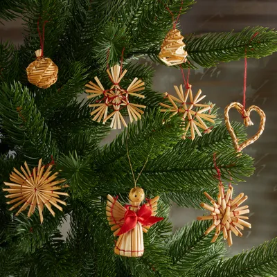 Various straw ornaments hanging on a Christmas tree.
