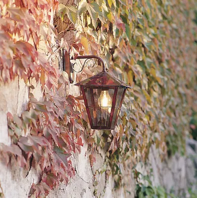 A vintage-style lantern mounted on a stone wall covered in ivy.