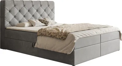 A studio shot of a gray upholstered boxspring bed with a tufted headboard and crystal accents, featuring a mattress, topper, and bedding.