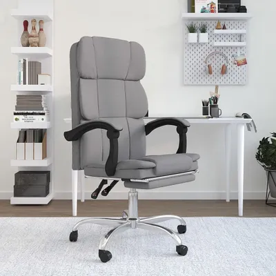 A grey fabric office chair with a footrest is shown in a room with shelves and a desk.