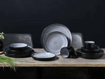A set of stoneware dishes is arranged on a wooden table against a dark background.