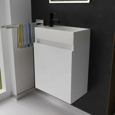 A modern white bathroom vanity with a sink and faucet against a dark textured wall.