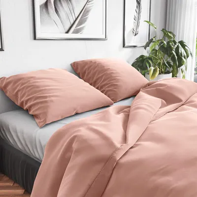 A close-up view of a bed with pink bedding and pillows.