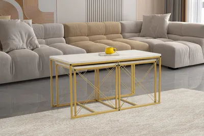 A set of nesting coffee tables with white tops and gold metal frames, placed in front of a sectional sofa in a living room setting.