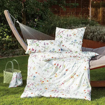 Bedding set with a floral pattern laid out on a hammock in a garden setting.