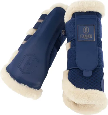 A pair of navy blue horse leg protection boots with cream faux fur lining.