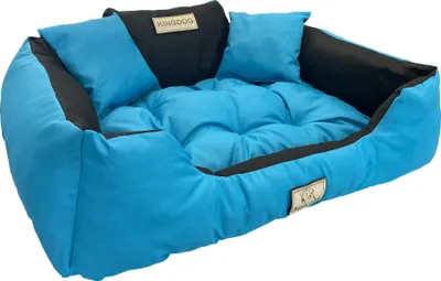 A blue dog bed with black accents and two small pillows.