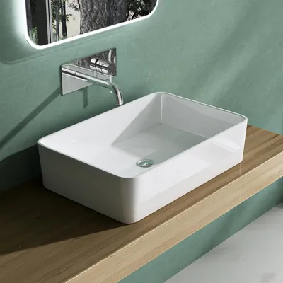 A modern bathroom sink on a wooden shelf with a green wall and a mirror.
