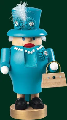 A wooden nutcracker shaped like Queen Elizabeth II, dressed in a turquoise outfit and hat, holding a small handbag.