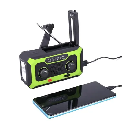 A solar-powered crank radio with a flashlight is shown connected to a smartphone, which is charging.