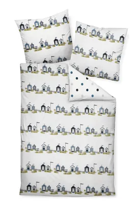A flat lay of bedding with a beach house pattern and a polka dot accent pillow.