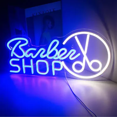 A neon sign for a barber shop, with blue and white lights, displayed in a room.
