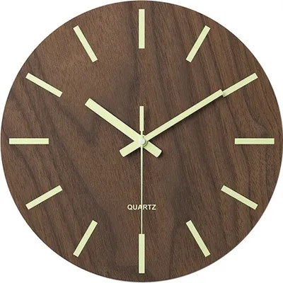 A close-up view of a round, wooden wall clock with luminous hour markers and hands.