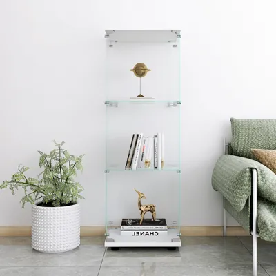 A glass display shelf with decorative items and books, next to a sofa and a potted plant.