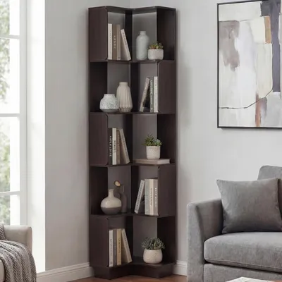 A corner bookshelf filled with books and decorative items, next to a window and a sofa.