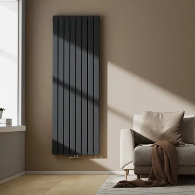 A modern living room with a dark gray vertical radiator next to a window and a beige sofa with a brown throw blanket.