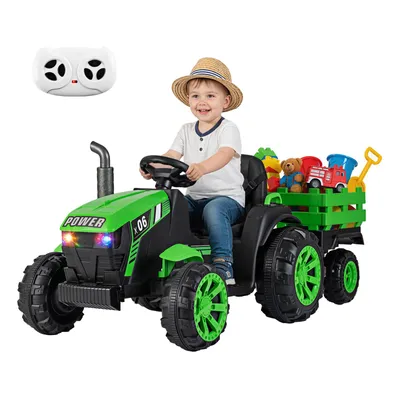 A child is riding a green toy tractor with a trailer full of toys.