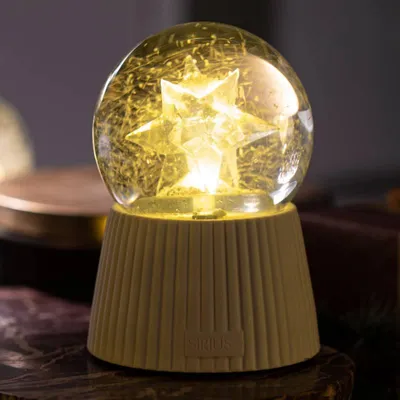 A close-up shot of a decorative snow globe with a star inside, placed on a marble surface.