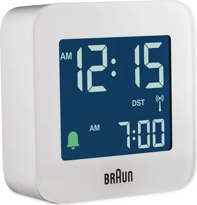 A white Braun alarm clock with a blue digital display showing the time and alarm settings.