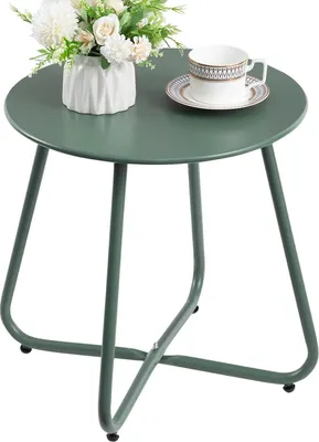 A green metal side table with a vase of flowers and a cup of tea on top.