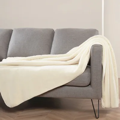 A cream-colored blanket draped over a gray sofa.