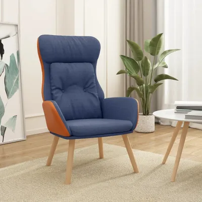 A blue and orange lounge chair is placed on a light beige rug in a room with a plant and a table in the background.