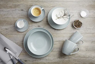 A collection of tableware, including cups, bowls, and plates, arranged on a wooden surface.