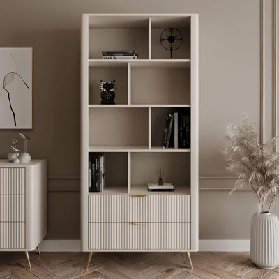 A beige bookshelf with drawers, decorated with books and ornaments, in a room setting.