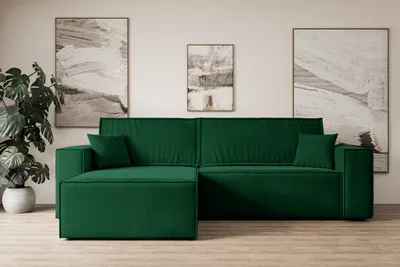 A green sectional sofa is shown in a well-lit room with abstract art on the wall and a large potted plant.