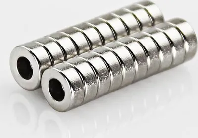 Two stacks of small, cylindrical magnets with holes in the center, placed on a white surface.
