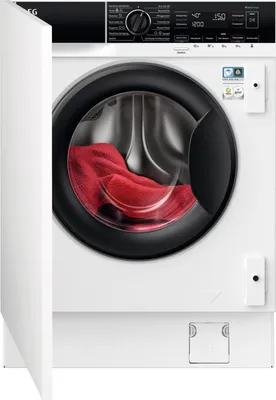 A front-on view of a white, built-in washing machine with its door slightly ajar, revealing a red garment inside.