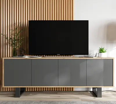 A TV stand with a television on top, placed in a room with wooden slat wall paneling.