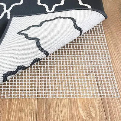A rug pad is shown underneath a rug on a wooden floor.