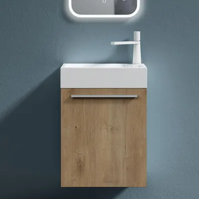 A modern bathroom vanity with a white sink and a wood-grain cabinet against a blue wall.