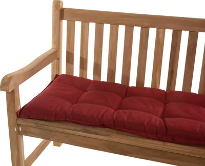 A close-up of a red cushion on a wooden garden bench.