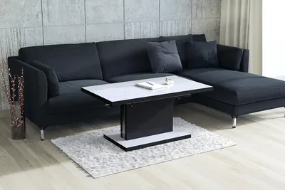 A modern living room with a dark gray sectional sofa and a white and black coffee table.