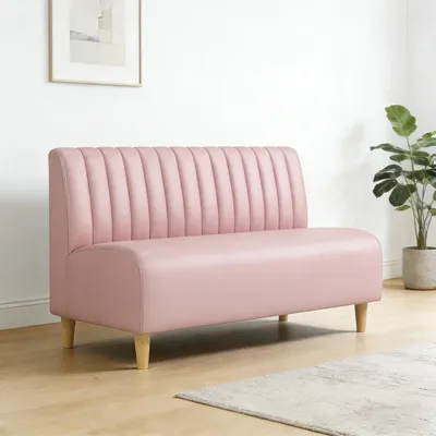A pink sofa in a room with a plant and a picture on the wall.